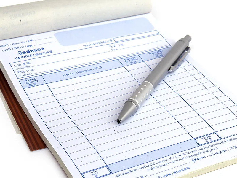 A carbonless invoice pad with a pen